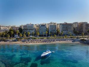 a boat in the water next to a beach at Coral Hotel Athens in Athens