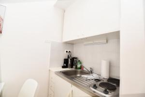 格拉茨Flataid CityAPART Lendplatz Neubaugasse的一个带水槽和白色橱柜的小厨房