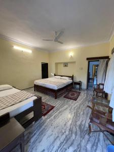 Un dormitorio con dos camas y un ventilador de techo. en Anandmai Heritage Villa Mount Abu, en Delmāra