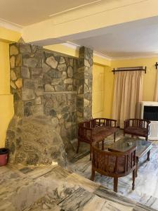 Habitación con una pared de piedra con mesas y sillas. en Anandmai Heritage Villa Mount Abu, en Delmāra