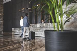 a man and woman walking through a lobby with their luggage at The Icon Limassol in Limassol