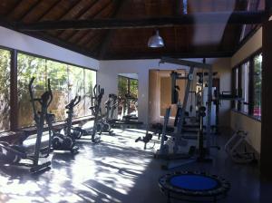 un gimnasio con cintas de correr y elípticas en una habitación con ventanas en Nannai Residence, en Porto de Galinhas