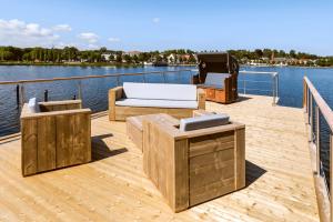 a wooden deck with two chairs and a grill on the water at Hausboot TreibGut in Fehmarn
