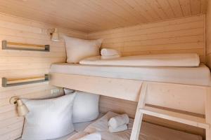 two bunk beds in a wooden cabin with pillows at Hausboot TreibGut in Fehmarn