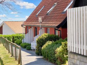 a red house with a red roof next to a fence at 5 person holiday home on a holiday park in Gudhjem in Gudhjem +43 photos