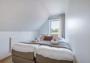 a large bed in a white room with a window at Vakantiehuis van Damme tot duin in Damme