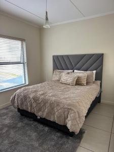 a bedroom with a large bed with a gray headboard at Greenstone ridge in Johannesburg