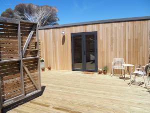 a wooden deck with a fence and a patio at Bastu Bicheno Tiny home in Bicheno