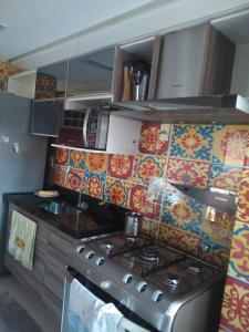 cocina con fogones y azulejos coloridos en la pared en Eco Residência, en Ananindeua