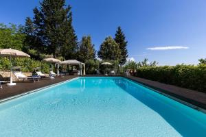a blue swimming pool with chairs and umbrellas at Tenuta Macericca by PosarelliVillas in Piecorto