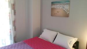 a bedroom with a pink bed and a picture of a beach at Dasea Houses in Ormos Panagias