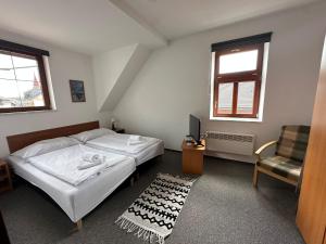 a bedroom with two beds and a tv and a chair at Kvildahotel in Kvilda