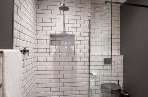 baño de azulejos blancos con ducha y aseo en Haisley Hotel, en Hilton 14 fotos más