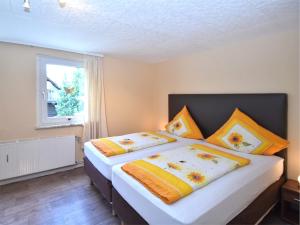 a bedroom with two beds with orange and yellow pillows at Entspannender Skiurlaub in Braunlage in Hohegeiß