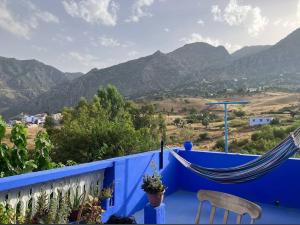 a hammock on a blue fence with mountains in the background at dar naim in Chefchaouen
