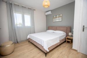 Un dormitorio con una cama con sábanas blancas y una ventana. en Elea Home, en Nea Vrasna