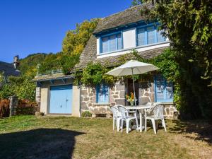 a table and chairs with an umbrella in front of a house at Vic-sur-Cère Family Nest in Vic-sur-Cère