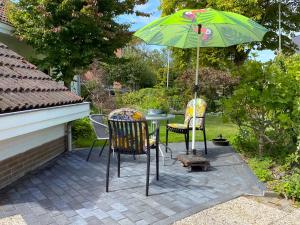 a patio with a table and chairs and an umbrella at Gezellige vakantiewoning dichtbij centrum Domburg DO20 in Domburg