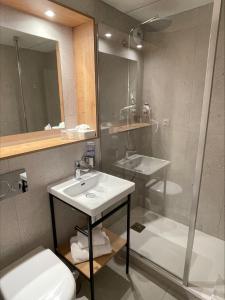 a bathroom with a sink and a toilet and a mirror at The Originals City, Hôtel Le Pavillon, Béziers Est in Béziers