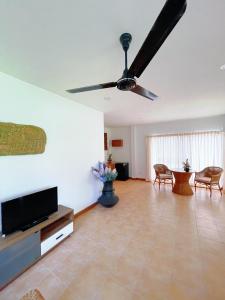 a living room with a flat screen tv and a ceiling fan at The Rinra Kamala Hut in Kamala Beach