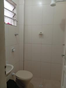 une salle de bain blanche avec toilettes et douche dans l'établissement Casa Praia Mongagua - Cantinho Familia pé na Areia, à Mongaguá 4 autres photos