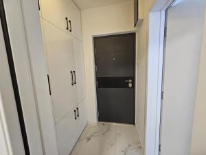 a hallway with white cabinets and a black door at Stan na dan - zvijezda Danica Kozarska Dubica in Bosanska Dubica