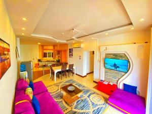 Shanzu Oceanline Apartments and Suites في مومباسا: غرفة معيشة مع أريكة أرجوانية ومطبخ