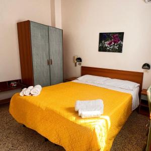 a hotel room with a yellow bed with towels on it at HOTEL BLUE SKY in Rimini +7 photos