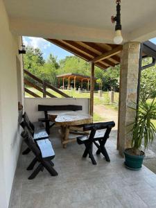 a patio with a picnic table and benches on a porch at Mia Hill House Nemenikuce in Nemenikuće