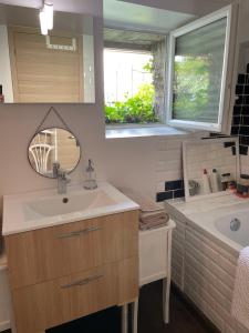a bathroom with a sink and a tub and a mirror at La Maison Rouge in Trouville-sur-Mer