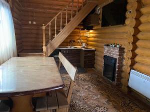 a wooden dining room with a table and a fireplace at Будинок з лазнею та басейном Дві години бані у вартості in Pukhovka
