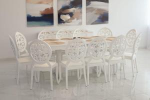 a white dining room table with white chairs and paintings at Flori House in Deva