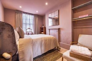 a bedroom with a bed and a chair and a window at The Rokxy Townhouses & Residences - Kings Cross in London