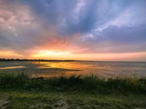 a sunset on a beach with the ocean at 14 person holiday home in Hadsund in Hadsund
