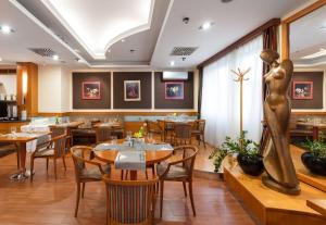 a restaurant with tables and chairs and a woman statue at Hotel Kálvária Superior in Győr