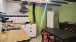 a kitchen with green walls and a table and a sink at Casa Jacobin in Ayerbe