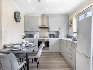a white kitchen with a table and chairs at Lavish 1 Bedroom Apartment in London