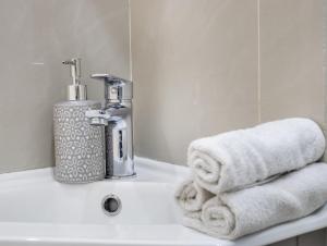 a bathroom sink with towels and a faucet at Lavish 1 Bedroom Apartment in London