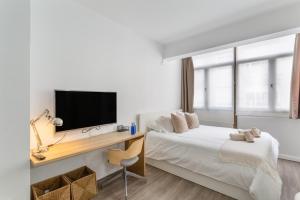 ein Schlafzimmer mit einem Bett und einem Schreibtisch mit einem Fernseher in der Unterkunft Siempreviva Beach Las Canteras in Las Palmas de Gran Canaria