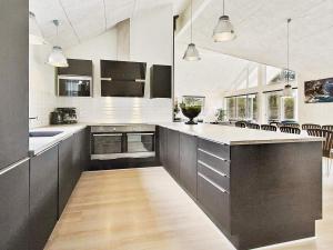 a large kitchen with black cabinets and white counters at 5 star holiday home in Liseleje in Liseleje