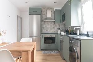 a kitchen with green cabinets and a wooden table at Amplio y reformado apartamento centro Santander in Santander +17 photos