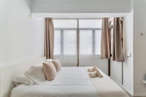 ein Schlafzimmer mit einem weißen Bett mit einem Fenster in der Unterkunft Siempreviva Beach Las Canteras in Las Palmas de Gran Canaria