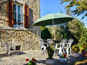 a table and chairs with a green umbrella at Sénezergues Garden Hideaway in Cassaniouze