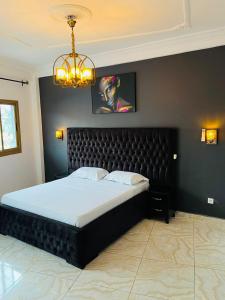 a bedroom with a large bed with a black headboard at résidence o-calme in Yaoundé