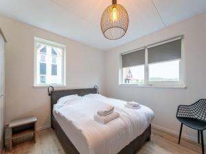 a bedroom with a bed and two windows at Modern holiday home by the sea with sauna in Scherpenisse