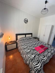 a zebra print bed in a bedroom with a clock on the wall at Kleines Paradies in der Nähe des portugiesischen Venedigs in Ponte de Vagos