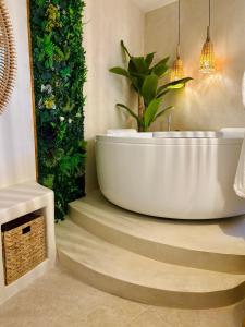a bath tub in a bathroom with a plant at Suite Myria, Balnéo & Cinéma - 1 heure de Paris in Maintenon +14 photos