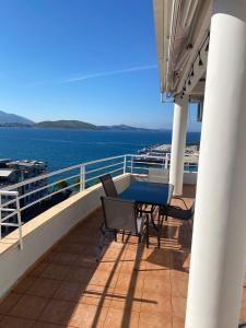 een tafel en stoelen op een balkon met water bij Saranda Sea View Apartment in Sarandë +1 foto