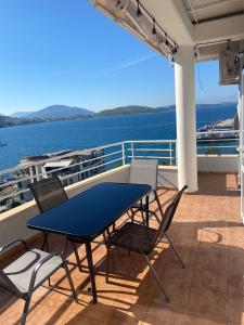 een tafel en stoelen op een balkon met uitzicht op het water bij Saranda Sea View Apartment in Sarandë