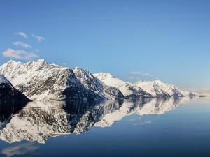 a reflection of snow covered mountains in a body of water at 9 person holiday home in Lyngseidet in Lyngseidet